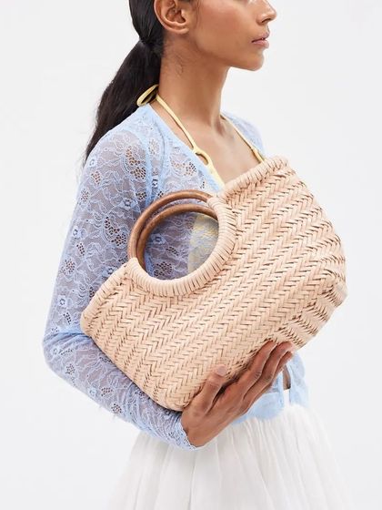 The handwoven Gambino Clutch in a neutral bisque color. The circular wooden handles add a natural, elegant touch to this spacious summer style.