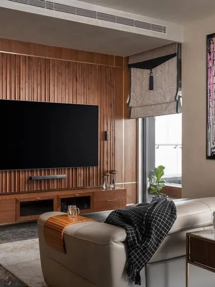 The media room from our "Quintessence" project, designed for entertainment and relaxation. The custom wood-paneled wall integrates the television and sound system, while playful art adds a touch of fun to the sophisticated space.
