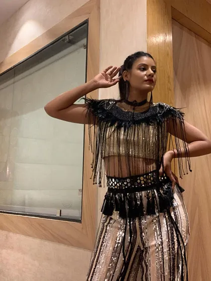 A pre-show moment before hitting the stage. The costume's design incorporates feathers and tassels that come alive during the dance, adding another layer of dynamism to the choreography.