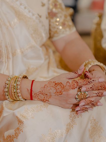 A detail shot of the mother of the groom's hands, adorned with beautiful henna and traditional bangles that complete her wedding look.