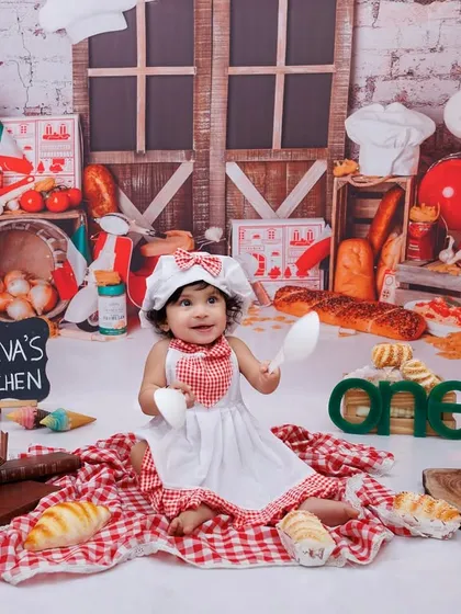 A wide shot of the "Jeeva's Kitchen" first birthday theme, showing the full setup with props like bread, a scooter, and a chef's hat.