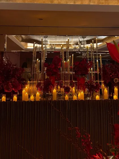 For a luxurious home birthday, we created a dramatic atmosphere using masses of crimson flowers and glowing candles on mirrored and metallic surfaces to reflect the light beautifully.
