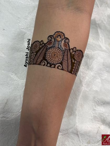 A close-up of an arm band for an engagement design, featuring parrots and floral motifs.