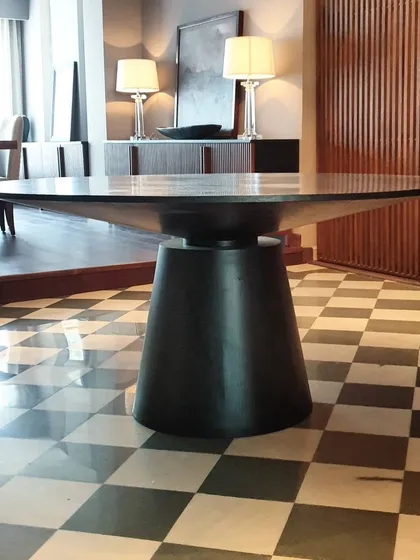 Here is another view of one of our favorite dining tables, showcasing its solid, conical base and expansive top. The dark finish gives it a commanding presence, perfect for modern and classic interiors alike.