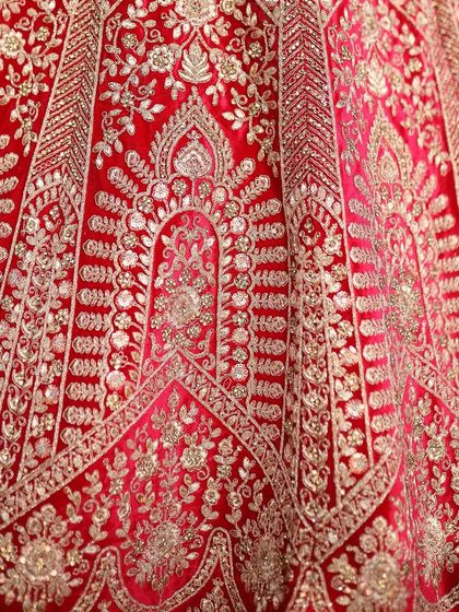 A close-up of the golden threadwork on a red bridal lehenga. This detailed craftsmanship is what makes my custom ethnic wear so special.