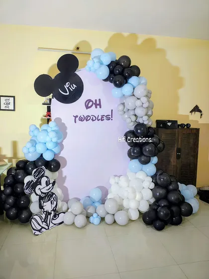 A modern and stylish take on a Mickey Mouse theme with an "Oh Twoddles!" concept. The decor uses a clean black, white, and baby blue color palette with a minimalist backdrop and balloon garland.