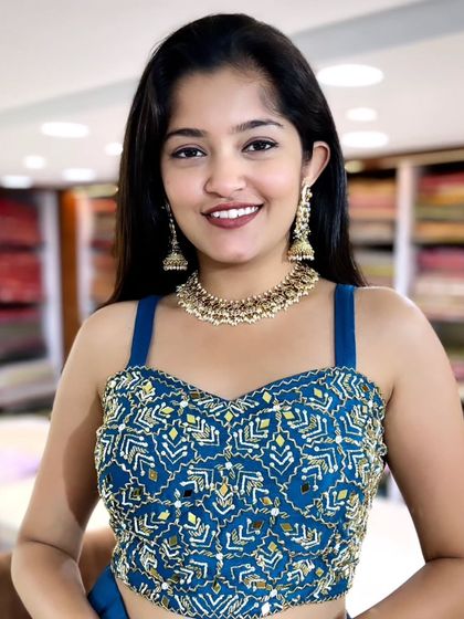 This model is wearing a beautiful stone and pearl necklace that perfectly matches her blue and gold outfit.