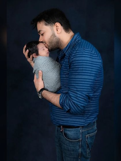 A tender moment as a father kisses his swaddled newborn's forehead. The black and white edit adds a timeless and emotional quality to this image.
