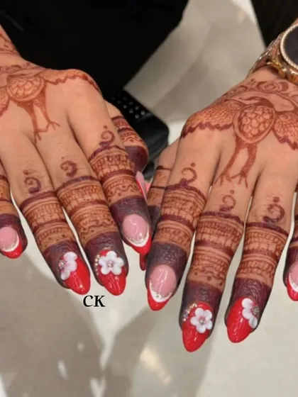 A full view of the red floral bridal nails, showing how the design complements the intricate peacock mehndi art.