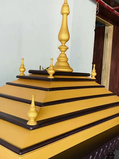 A close-up of the shikhara, or roof, of the mandir. The tiered design is finished with gold paint, adding a touch of divine opulence to this sacred piece of furniture.