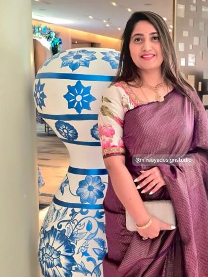 A client looking elegant in a purple tissue silk saree. Her custom floral print blouse adds a touch of modern femininity to the traditional drape.