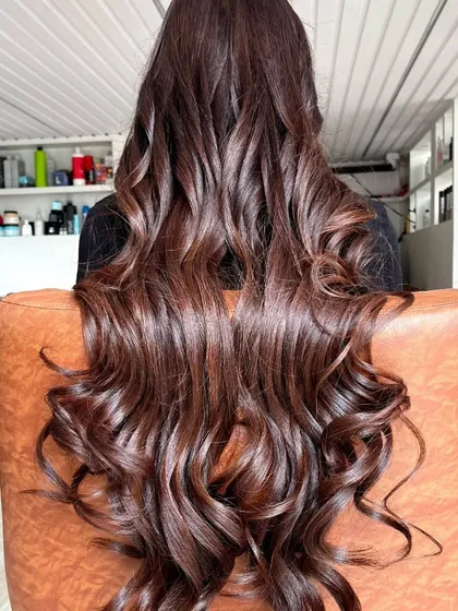 A beautiful final look of a rich chocolate brown color service. The hair is styled in deep, cascading curls to showcase the multi-tonal quality and incredible shine of the new color.