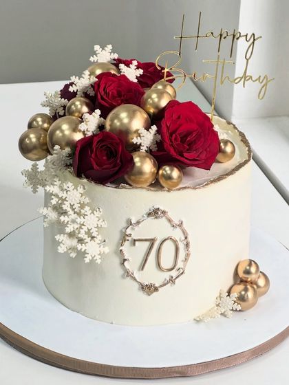 Celebrating 70 years of grace and love. This elegant milestone cake is designed with timeless red florals, golden spheres, and delicate snowflake details for a truly special occasion.