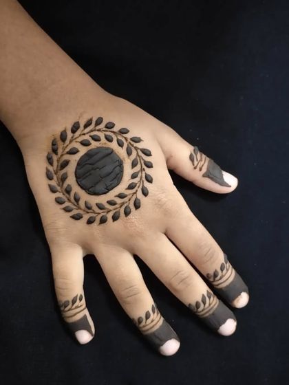 A close-up of the simple leaf-wreath mandala on a child's hand.