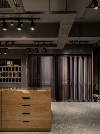 Another view of the main showroom floor, highlighting the industrial ceiling with its exposed ductwork and track lighting, which contrasts with the warm wood furniture.