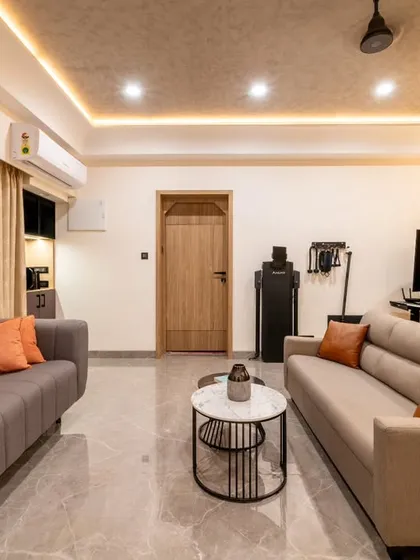 The fully transformed multi-purpose room, now a cohesive space for relaxation and activity. We integrated two distinct seating areas, a gaming station, and an exercise machine, using a consistent color palette and lighting to unify the different zones.