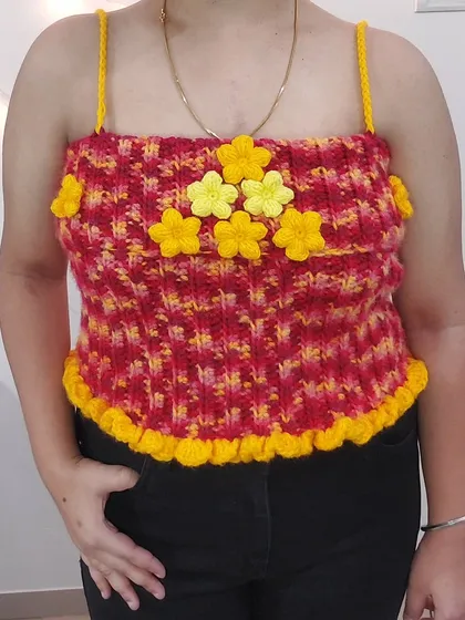 This is the Daisy Babe Top, a fun corset-style piece with a vibrant red and yellow pattern and adorable daisy embellishments.