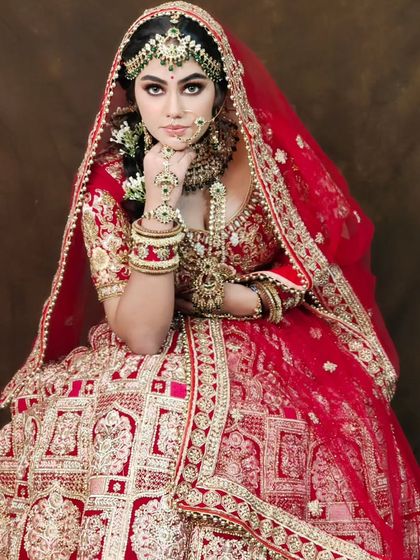 A stunning bride in a heavily embellished red lehenga with intricate doli patterns. This is a premium designer piece that will make you feel like a queen on your wedding day.