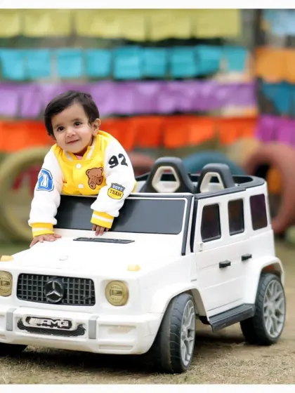 A little boy looking proud in his toy Mercedes. Our outdoor shoots with colorful backgrounds are always a hit with the kids.