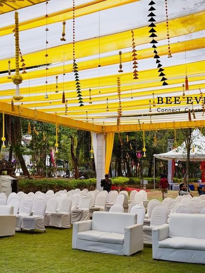 An outdoor seating area under a canopy of yellow and white drapes. This setup is perfect for guests at a Haldi or Mehendi function, providing a comfortable and beautifully themed space to enjoy the festivities.