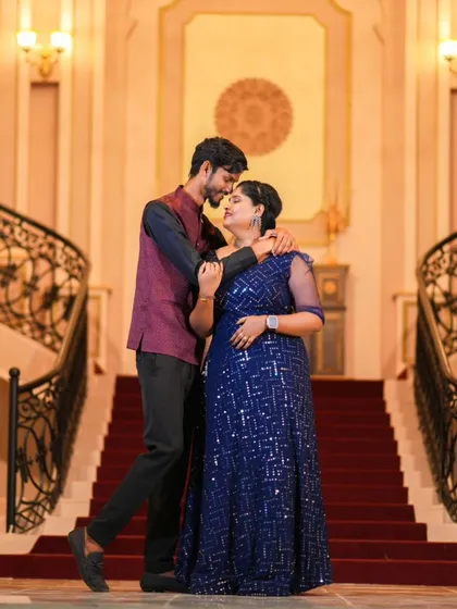 A romantic pose on a grand staircase. The couple's elegant blue and maroon outfits look stunning in this palace-like setting.