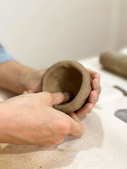 A student forms a small bowl using the pinching method, a fundamental skill we teach in our beginner hand-building classes.
