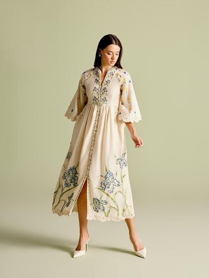 A full view of the embroidered midi dress, featuring bell sleeves and a slit, combining classic elegance with a modern cut.