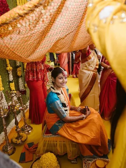 Another view of the bride during the Haldi ritual, showcasing the traditional canopy held by her family.