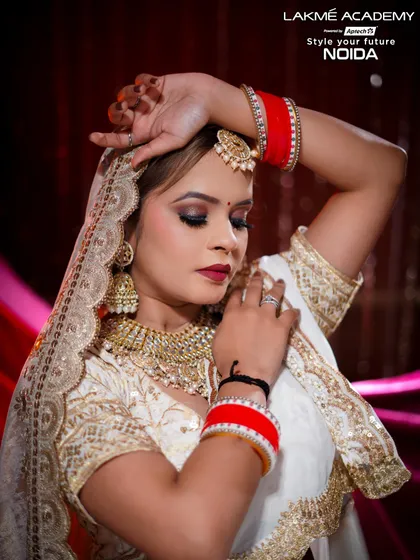 A soft and romantic bridal portrait. The focus is on the delicate jewelry, the red bangles, and the beautifully blended eye makeup, creating a timeless and elegant look.
