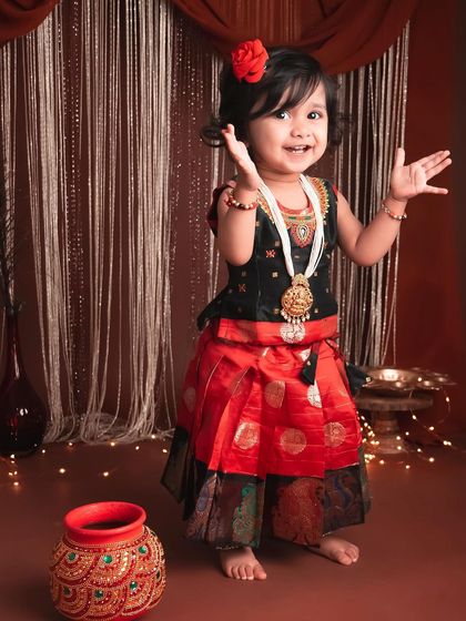 Such a happy and welcoming gesture from this little one. The vibrant colors of her outfit and the surrounding props make this a wonderfully lively photograph.