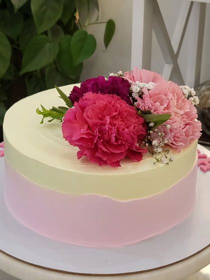A simple and elegant cake with two-toned frosting and a beautiful bouquet of fresh carnations on top. Sometimes, less is more.