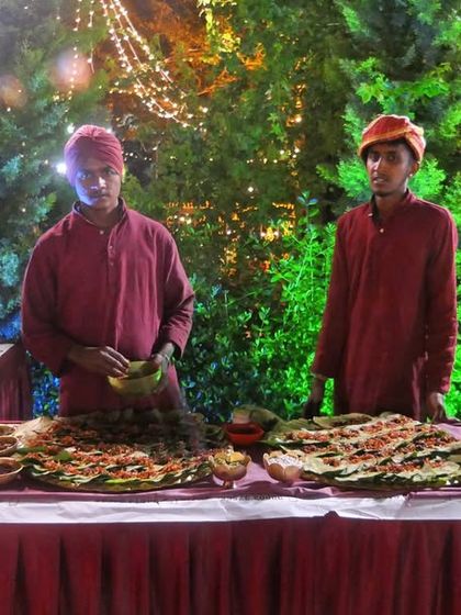 A live counter set against a backdrop of lush greenery and festive lights. My staff is ready to serve freshly prepared vegetarian starters to guests.