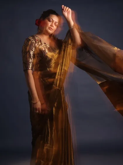 A retro-inspired look for Priyanka Barve. This shimmering gold saree paired with a brocade blouse and red flowers in her hair evokes a timeless, cinematic feel.