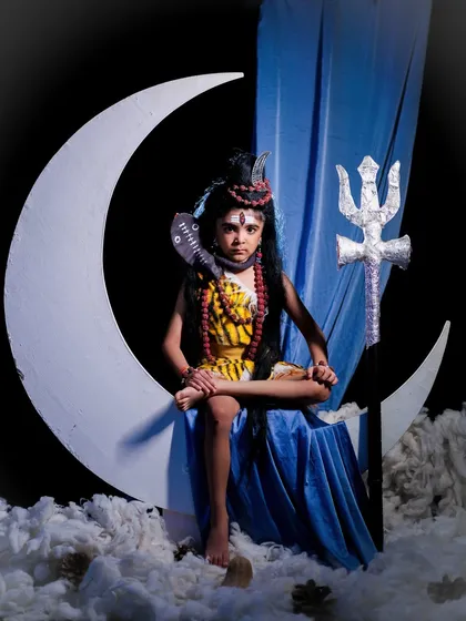 A dramatic and serene portrait of a child as Lord Shiva, seated in a meditative pose on a crescent moon against a dark background.
