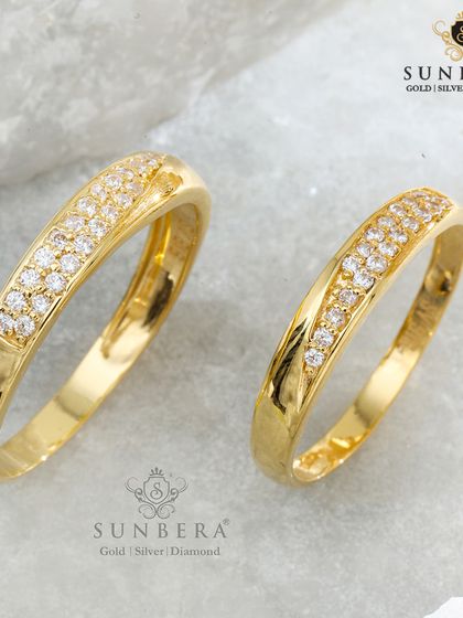 This pair of couple rings showcases a graceful wave of pavé-set diamonds across a smooth gold band. The design is both elegant and timeless, symbolizing the beautiful journey you share together.