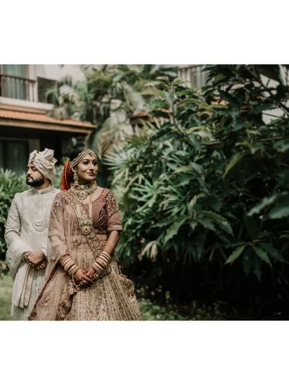 A stunning portrait of Shivangi and Kashyap on their wedding day. Posed against a lush green backdrop, this shot captures the elegance and poise of the couple in their traditional wedding attire.
