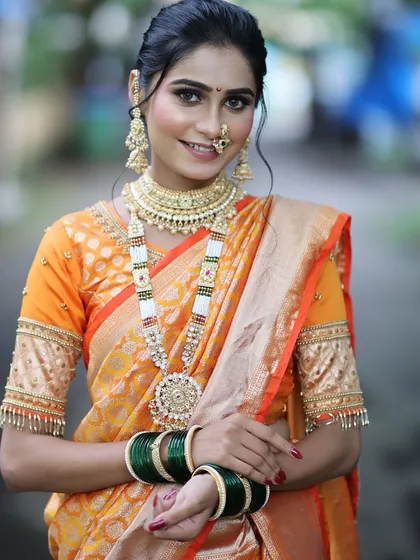 A smiling portrait of the bride, showing how the makeup looks natural and enhances her happiness. The green bangles and traditional jewelry complete the look.