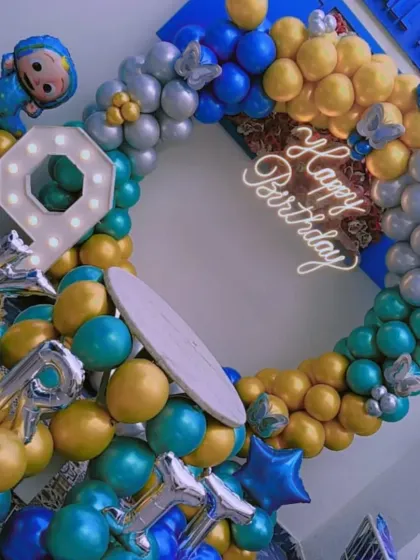 A Cocomelon-themed 9th birthday party. This full balloon ring uses blue, gold, and teal colors, with a Cocomelon character foil balloon and a light-up number '9'.