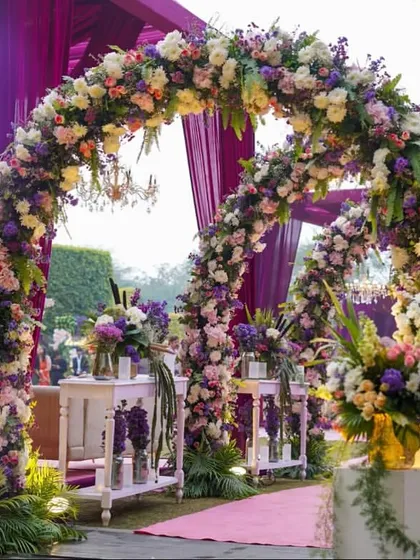 The entrance to a beautiful engagement ceremony, featuring cascading floral arches in pastel shades. The soft lighting and lush greenery create a dreamy and welcoming pathway for guests.