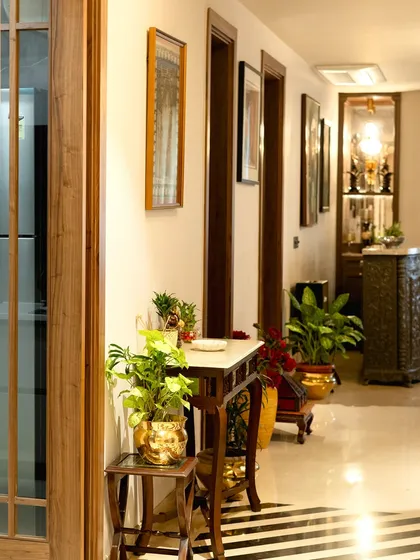 We use indoor plants to bring life and freshness into our interiors. In this elegant hallway, potted plants in traditional brass planters add a touch of green and complement the classic wooden furniture.