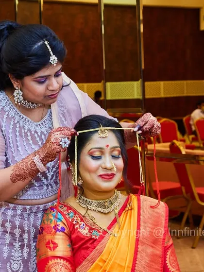 Capturing the final moments of preparation is key. This photo shows the bride getting help with her traditional headwear, surrounded by the warm ambiance of the getting-ready room.