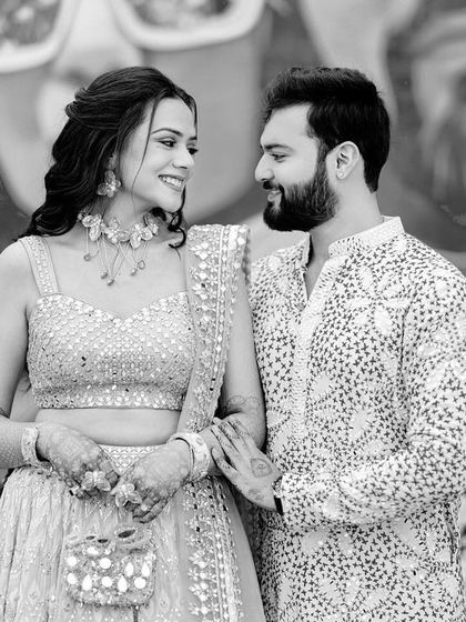 A sweet black and white candid of the couple sharing a look during their carnival-themed Mehendi, a quiet moment amidst the fun.