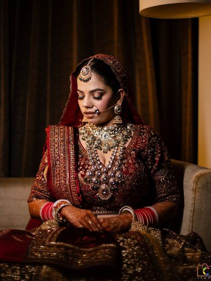 The bride Ashima in a moment of quiet contemplation. The soft, warm tones of her makeup create a look of timeless elegance.