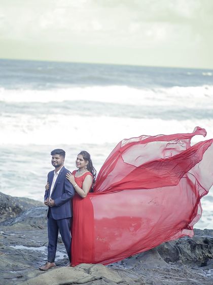A powerful pre-wedding stance on the rocks. The flowing red trail of the gown makes a bold statement against the sea.