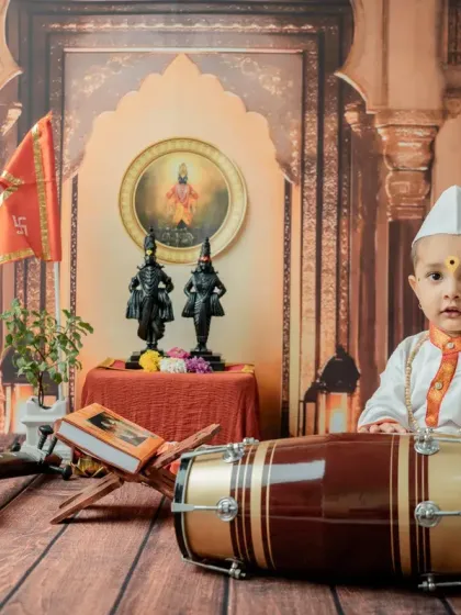 A seated pose with the dhol, capturing a moment of concentration. The warm, earthy tones of the backdrop add to the traditional feel.