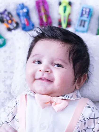 This three-month-old cutie is ready to race. Lying on his back, he is surrounded by an arc of colorful Hot Wheels cars.
