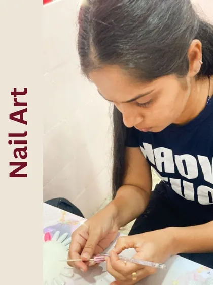 This student is practicing her nail art skills, carefully painting a design onto a practice tip.