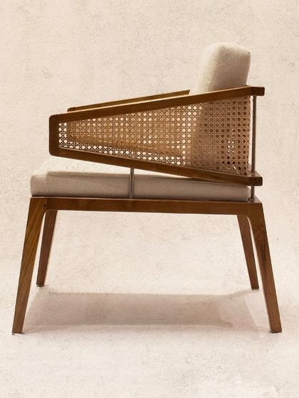 The 'Santoor' chair, with its distinctive triangular rattan armrests and comfortable cushions, offers a unique profile that stands out in any room.