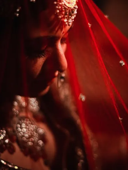 An artistic close-up of the bride, with the red veil creating a beautiful color cast and focusing on the details of her jewelry.