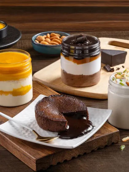 A dessert platter featuring a choco-lava cake with a molten center, alongside various jar desserts, showcasing a range of sweet treats.